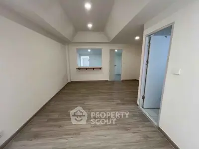 Spacious empty room with wooden flooring and recessed lighting, ideal for customization.
