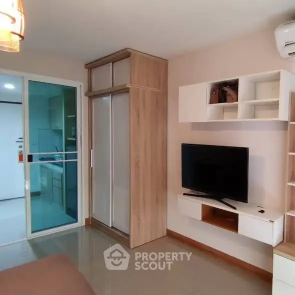 Modern living room with TV, stylish shelving, and sliding glass door to kitchen.