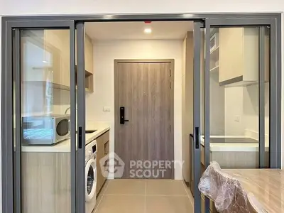Modern kitchen with sliding glass doors, featuring a washing machine and sleek cabinetry.
