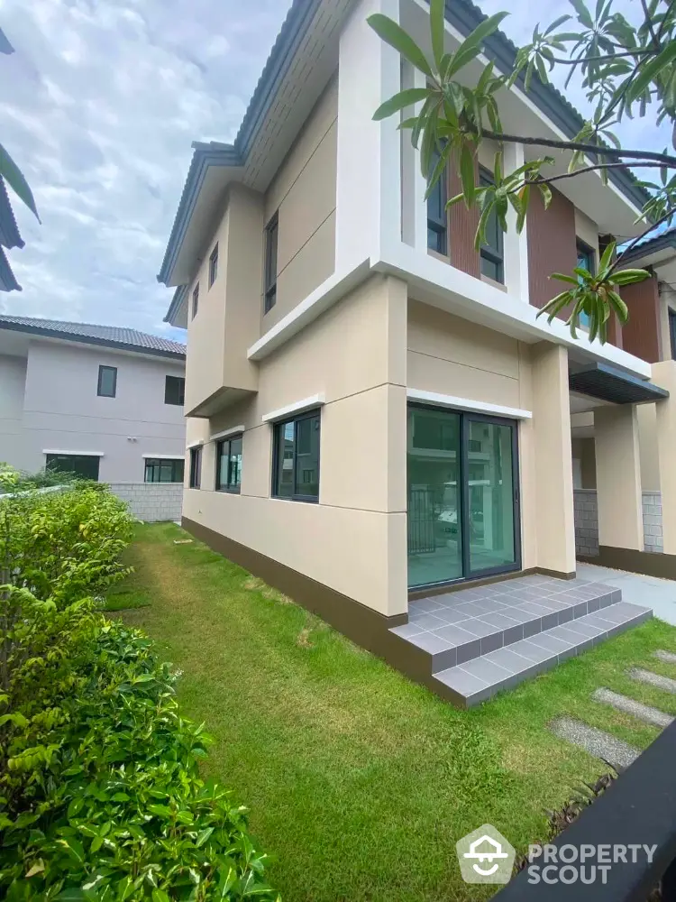 Modern two-story house with lush green garden and large windows