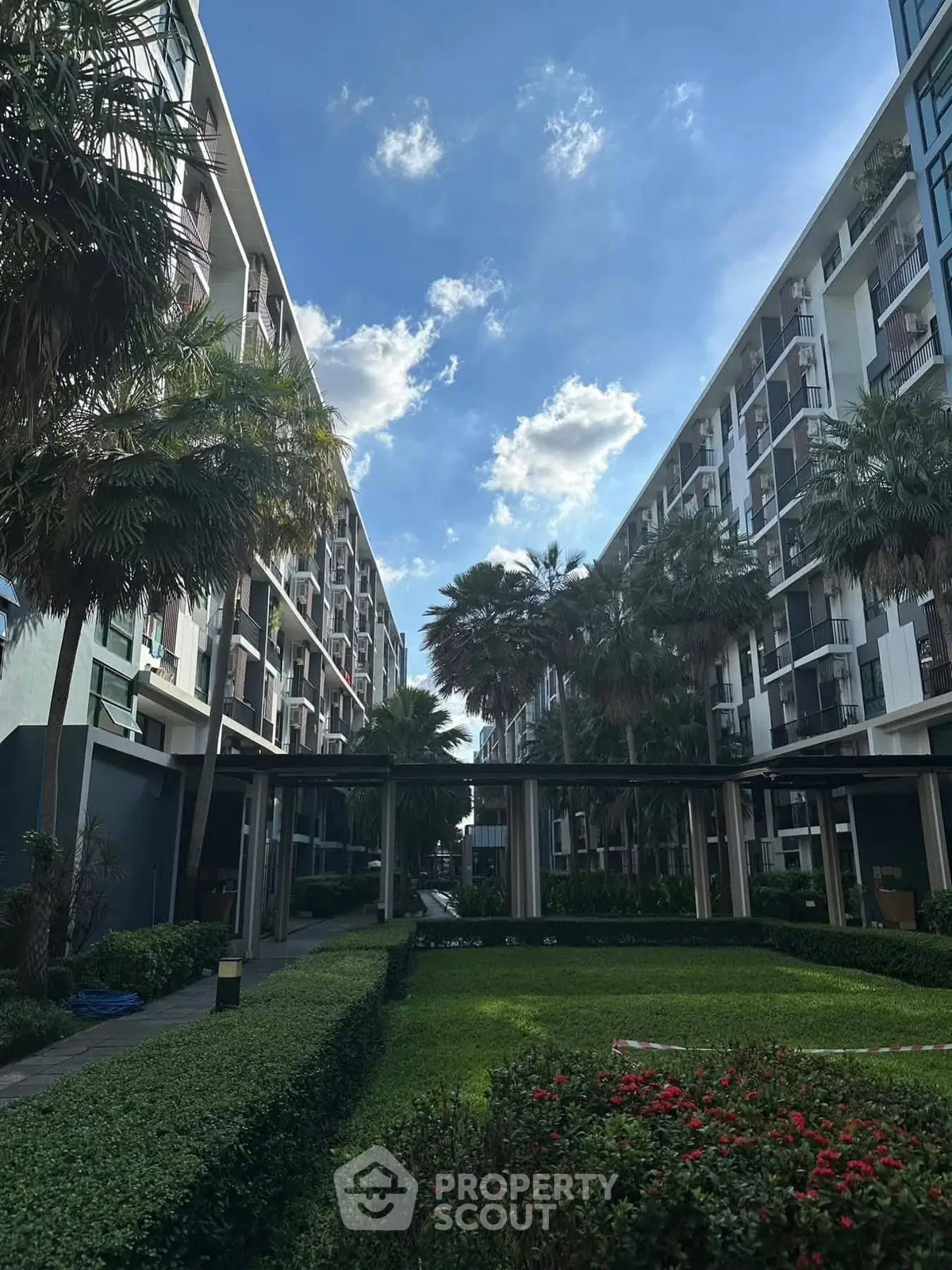 Modern apartment complex with lush garden and clear blue sky