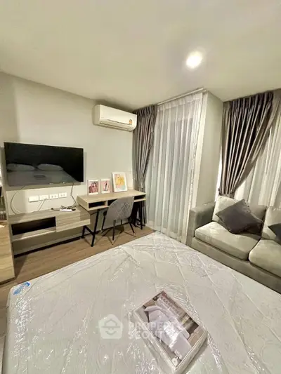 Modern bedroom with cozy seating area and workspace, featuring elegant curtains and ambient lighting.