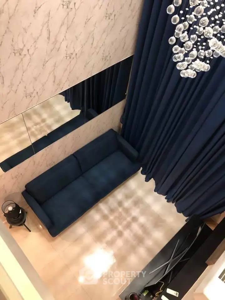 Elegant living room with blue sofa, marble walls, and luxurious chandelier