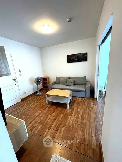 Modern living room with wooden flooring and cozy gray sofa in a stylish apartment.