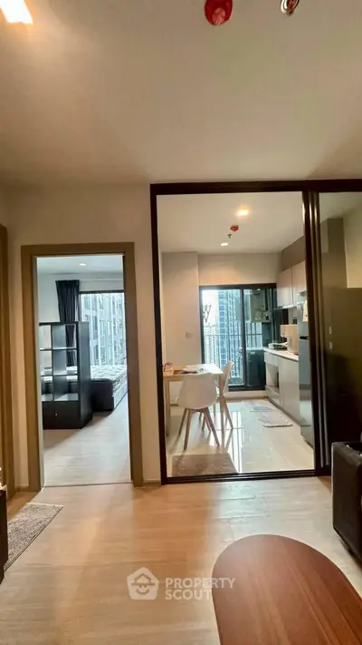 Modern open-plan apartment with kitchen and dining area, featuring sleek design and natural light.