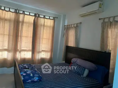 Cozy bedroom with large windows and air conditioning, perfect for relaxation and comfort.