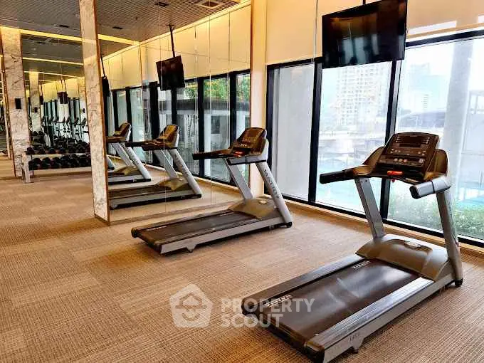 Modern gym with treadmills and large windows in luxury apartment building.