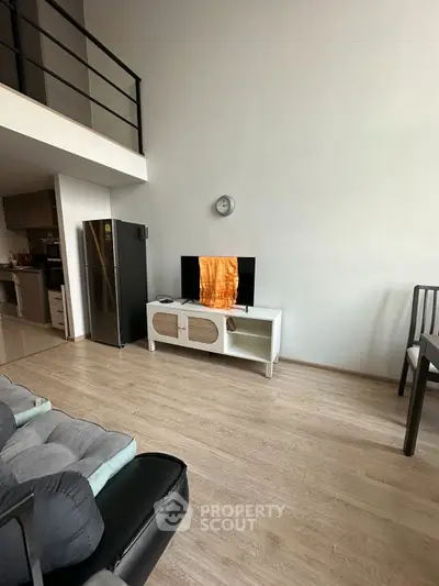 Modern living room with high ceiling, sleek furniture, and open kitchen layout in a stylish apartment.
