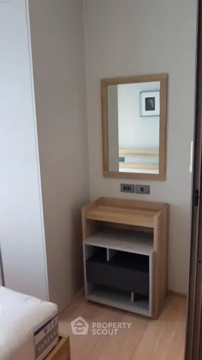 Modern bedroom corner with wooden dresser and mirror, ideal for compact living spaces.