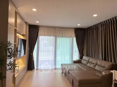 Spacious living room with modern sofa and large windows in elegant apartment.