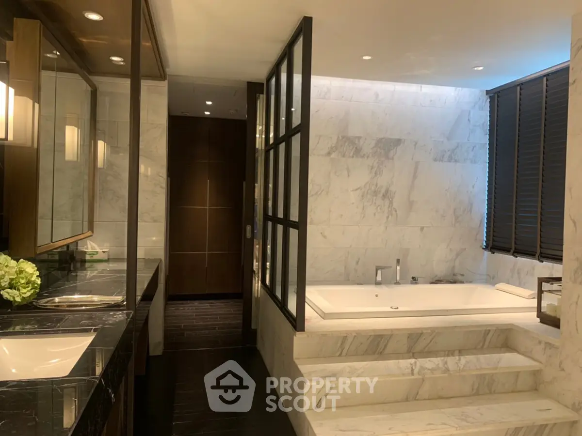 Luxurious marble bathroom with sunken bathtub and elegant lighting