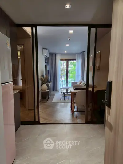 Modern living room with glass doors and elegant decor, featuring a cozy seating area and natural light.