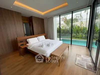Luxurious bedroom with pool view and modern wooden furnishings in a tropical setting.