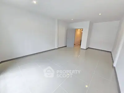 Spacious empty room with glossy tiled flooring and recessed lighting, perfect for customization.