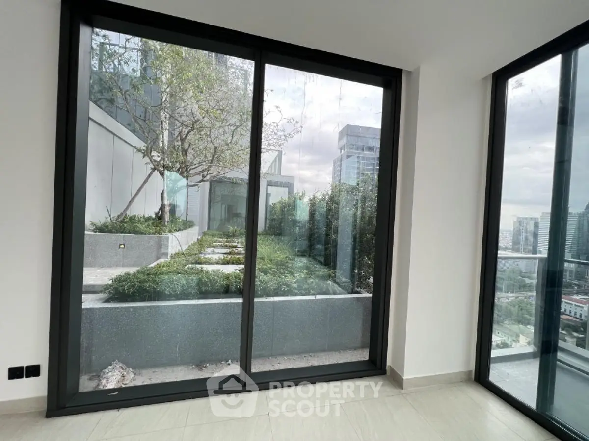 Modern apartment with large windows offering a stunning city view and lush greenery.