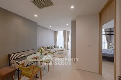 Modern open-plan living room with dining area and cozy bedroom view.