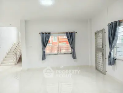 Spacious bright living room with large windows and modern staircase