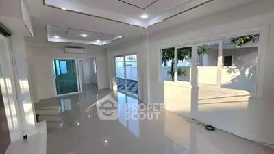 Spacious modern living room with large windows and glossy tiled floors, perfect for natural light lovers.