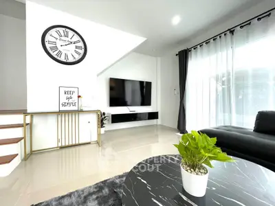 Modern living room with sleek black furniture, large TV, and stylish decor for a contemporary lifestyle.