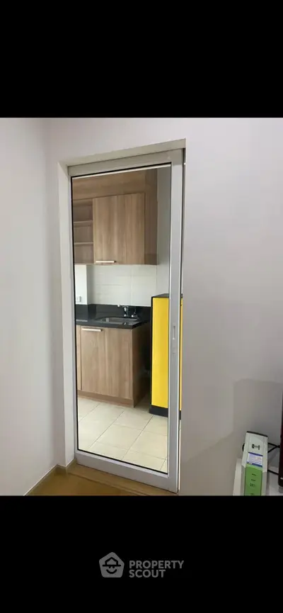 Modern kitchen with sleek cabinetry and glass sliding door in a contemporary apartment.