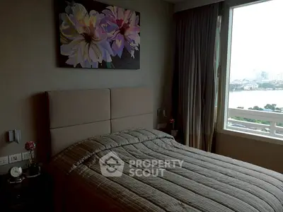 Cozy bedroom with large window offering stunning city view, elegant decor, and plush bedding.