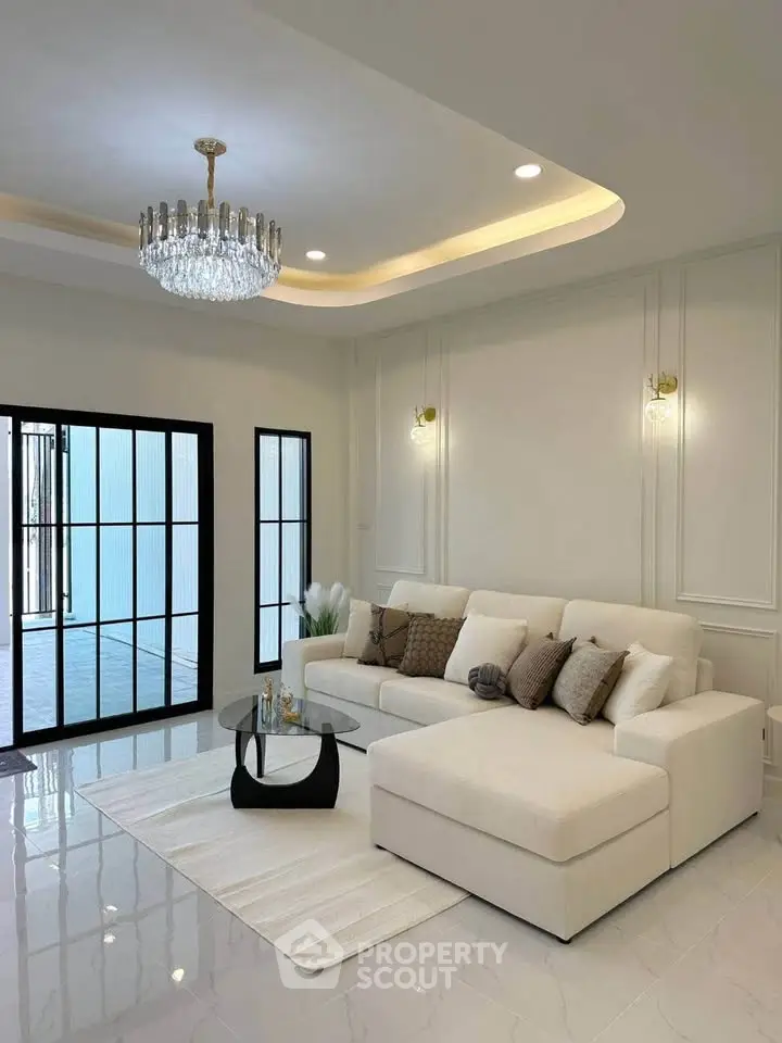 Elegant living room with modern chandelier and spacious white sectional sofa.