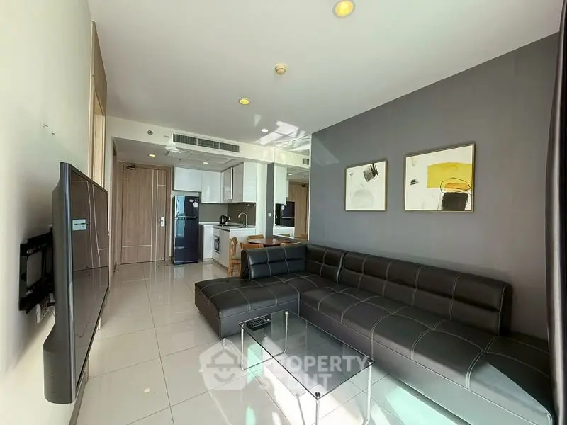 Modern living room with sleek black leather sofa and open kitchen layout