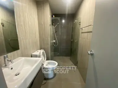 Modern bathroom with sleek design, featuring a glass shower and contemporary fixtures.