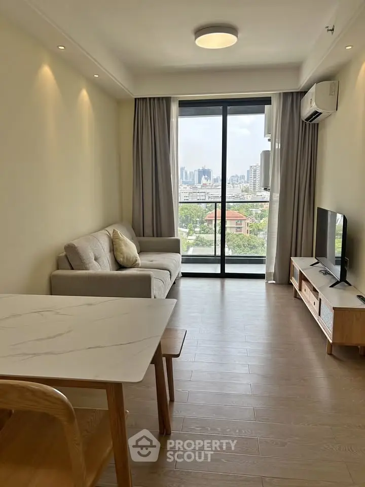 Modern living room with city view, featuring sleek furniture and large windows for natural light.