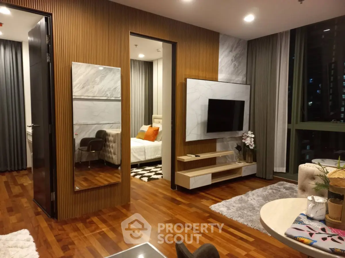 Luxurious modern living room with wooden flooring, stylish decor, and a glimpse into a cozy bedroom.