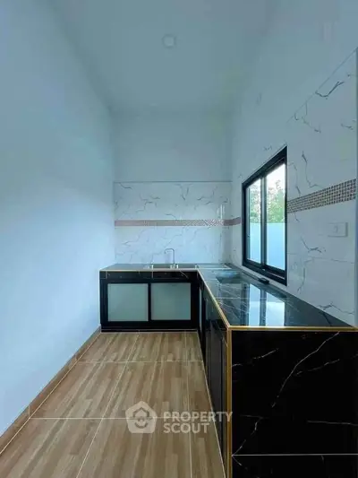 Modern kitchen with sleek black cabinetry and marble backsplash in a bright, airy space.
