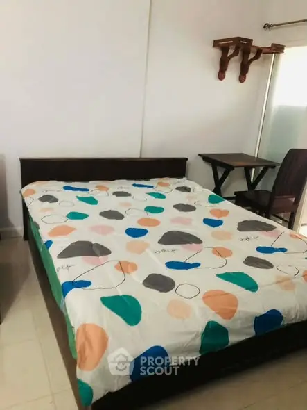 Cozy bedroom with colorful bedding and natural light, perfect for relaxation.