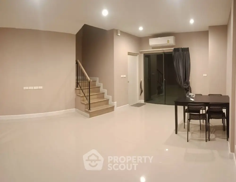 Spacious and modern living area with glossy tiled floors, elegant staircase, and ample lighting, perfect for family gatherings and entertainment.
