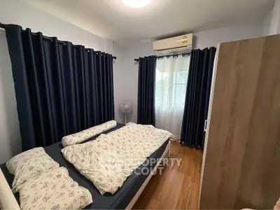 Cozy bedroom with wooden flooring, air conditioning, and dark curtains for a comfortable living experience.