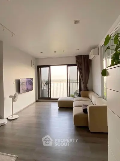 Modern living room with large windows and stunning view, featuring sleek furniture and elegant decor.