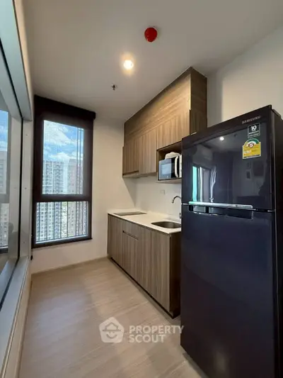 Modern kitchen with sleek cabinets and large window offering city views.