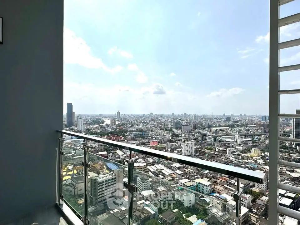 Stunning high-rise balcony view overlooking a vibrant cityscape under a clear blue sky.