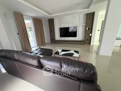 Spacious modern living room with sleek leather sofa and large TV, perfect for relaxation.