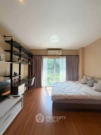 Spacious bedroom with large window and stylish decor, perfect for relaxation and comfort.