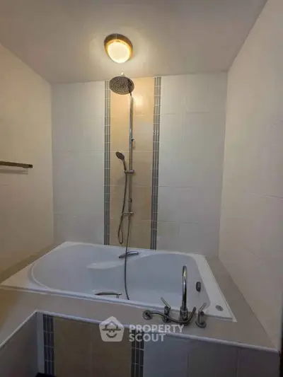 Modern bathroom with elegant bathtub and overhead shower, featuring sleek tile design and ambient lighting.