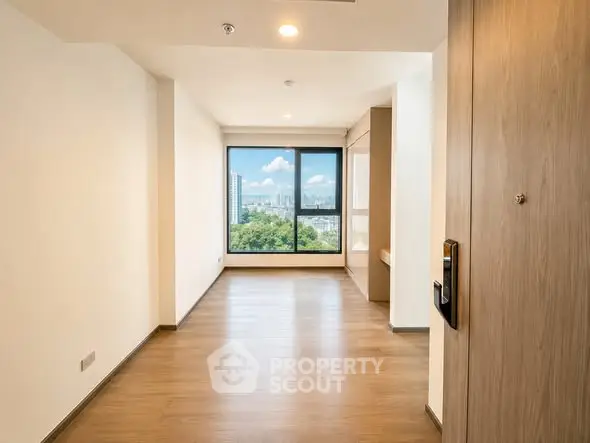 Spacious empty room with large window offering stunning city view, perfect for customization.