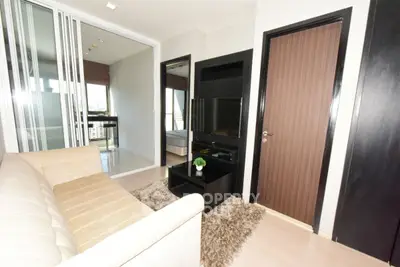 Modern living room with beige sofa and sleek black entertainment center.