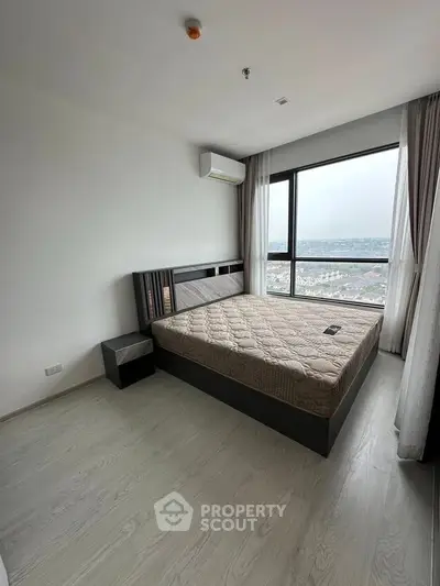 Modern bedroom with large window offering stunning city view, featuring sleek design and ample natural light.