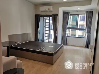 Spacious bedroom with modern design, large windows, and balcony access, featuring elegant drapery and ample natural light.