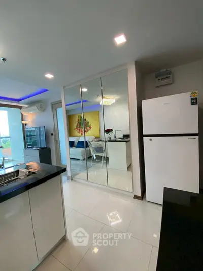 Modern kitchen with sleek white cabinetry and mirrored accents in a stylish apartment.