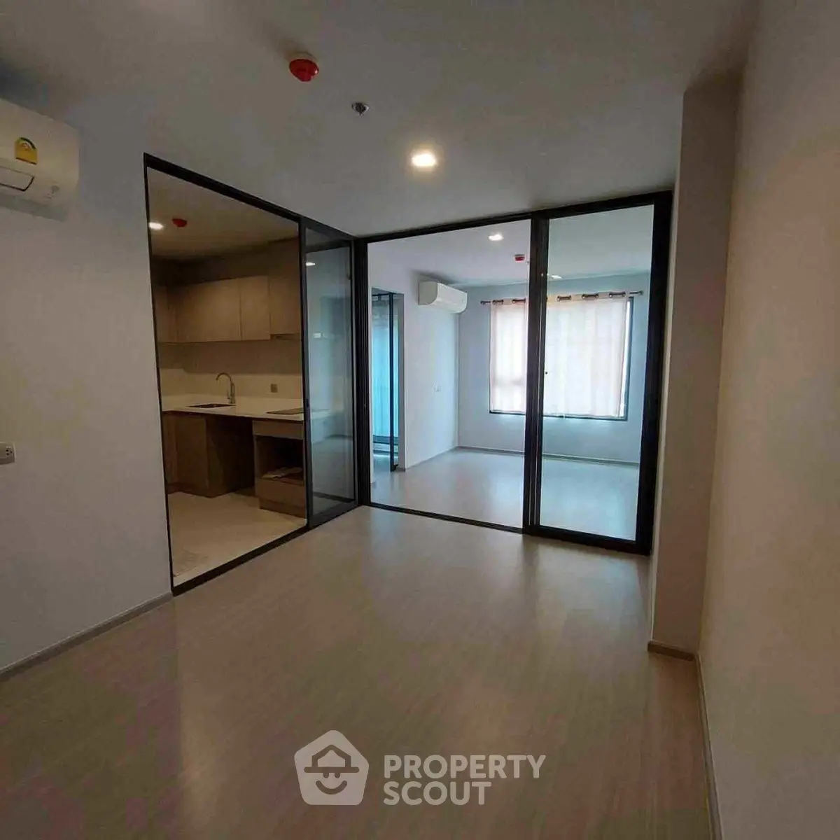 Modern apartment interior with glass partitions and sleek kitchen design.