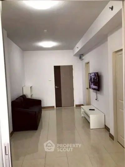 Spacious living room with modern sofa and wall-mounted TV in a contemporary apartment.