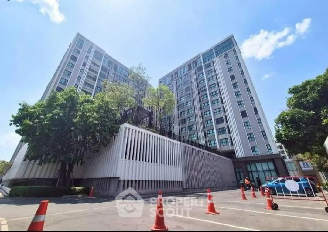 Modern high-rise building with sleek design and ample parking space, perfect for urban living.