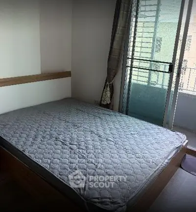 Spacious bedroom with large window and balcony access in modern apartment.