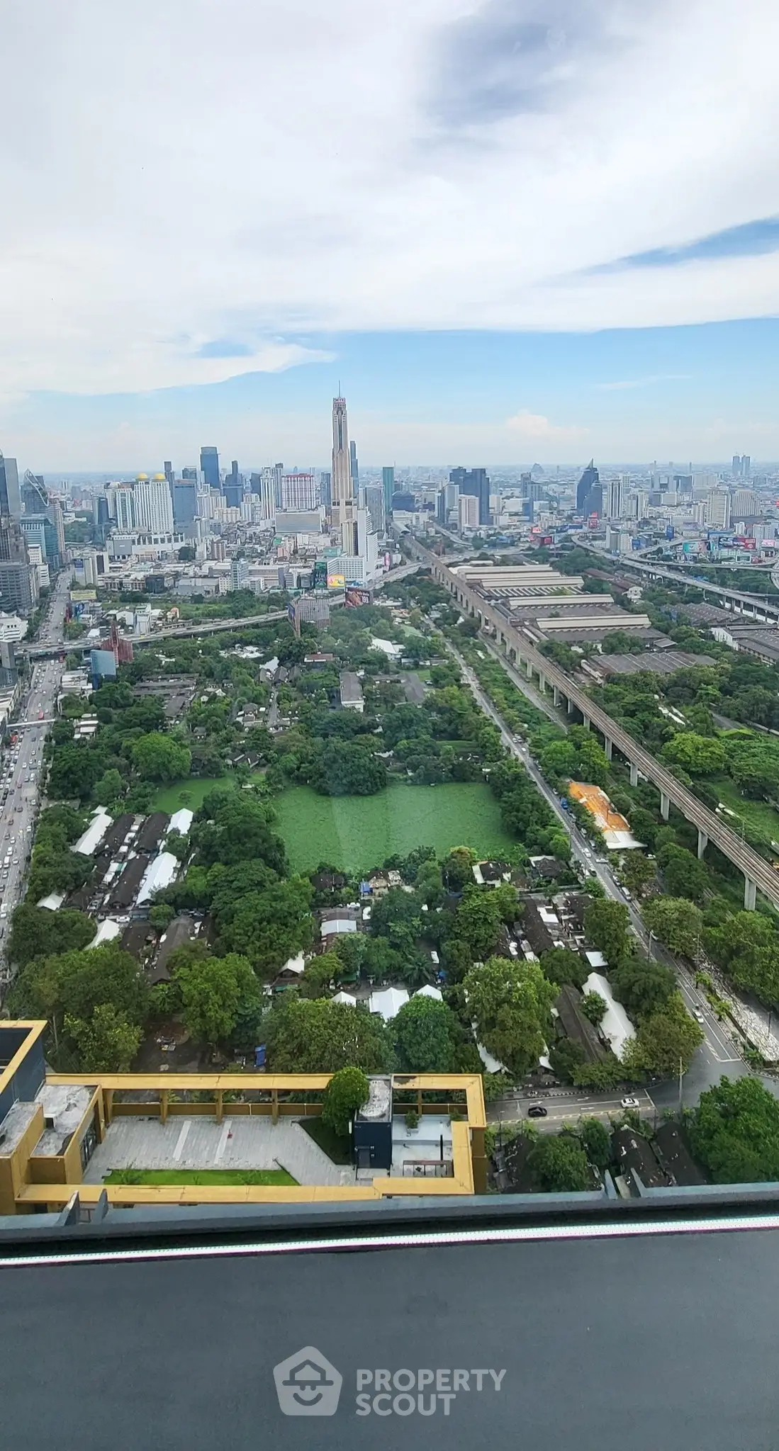 Stunning cityscape view from high-rise building showcasing urban skyline and lush greenery.